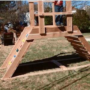 May include: Wooden outdoor playset with a slide, climbing wall, and ladder. The slide has colorful handholds and the climbing wall has wooden rungs. The playset is made of natural wood and is suitable for children.