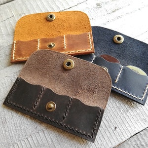 Puede incluir: Tres porta-púas de cuero en diferentes colores: marrón, marrón oscuro y negro. Cada porta-púas tiene tres ranuras para púas y un cierre de botón de latón.