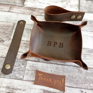 Dark brown tobacco tray, pipe stand and leather strap.