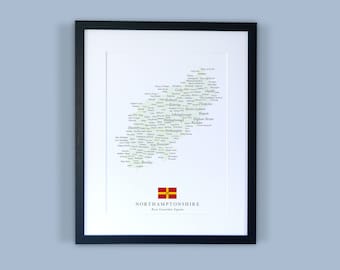 Könnte beinhalten: Ein gerahmter Druck einer Karte von Northamptonshire, England. Die Karte besteht aus den Namen der Städte und Gemeinden des Countys, die in einer Form angeordnet sind, die der Umriss des Countys nachahmt. Die Karte ist in Schwarzweiß gedruckt, mit einem grünen Umriss des Countys. Der Rahmen ist schwarz und hat einen weißen Passepartout. Der Druck enthält auch die Flagge des Countys und die Worte "Northamptonshire" und "A County Celebrated Sign".