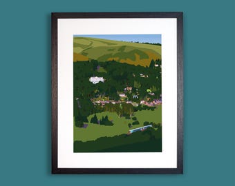 Könnte beinhalten: Ein gerahmter Kunstdruck mit einer stilisierten Landschaftsillustration eines Tals mit grünen Hügeln, dichten dunkelgrünen Wäldern und einer kleinen Ansammlung von Gebäuden inmitten der Bäume, eingefasst in einen schlichten schwarzen Rahmen.
