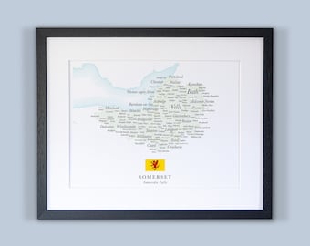 Könnte beinhalten: Eine Karte von Somerset, England, mit den Namen von Städten und Gemeinden in gelber Schrift auf weißem Hintergrund. Die Karte ist schwarz gerahmt und hat im unteren linken Eck ein rotes Drachenemblem. Der Text "SOMERSET" und "Somerset Kalle" ist unter der Karte gedruckt.