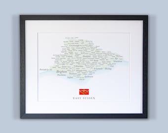 Może przedstawiać: Mapa East Sussex w Anglii, z nazwami miast i miasteczek wydrukowanymi na nim. Mapa jest oprawiona w czarną ramę i ma czerwoną i białą flagę w prawym dolnym rogu.