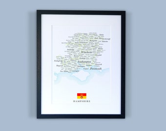 Może przedstawiać: Wzorowana mapa hrabstwa Hampshire w Anglii, z nazwami miast i miasteczek wydrukowanymi jasnozielonym kolorem. Mapa jest na białym tle z niebieskim efektem akwarelowym wokół krawędzi. Na dole mapy znajduje się mała czerwono-żółta flaga z koroną.