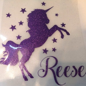 May include: Purple glitter unicorn silhouette with a horn and a tail, surrounded by stars. The name "Reese" is written in purple glitter below the unicorn.