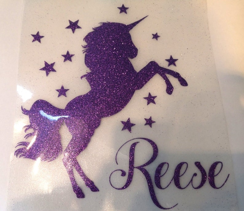 May include: Purple glitter unicorn silhouette with a horn and a tail, surrounded by stars. The name "Reese" is written in purple glitter below the unicorn.