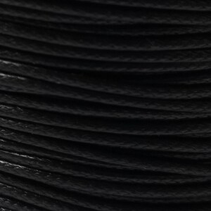 May include: Close-up of a spool of black waxed cotton cord.