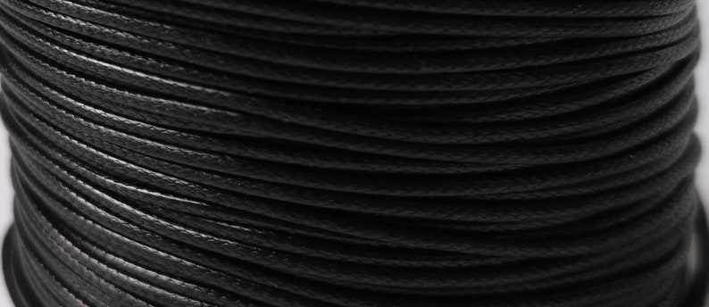 May include: Close-up of a spool of black waxed cotton cord.
