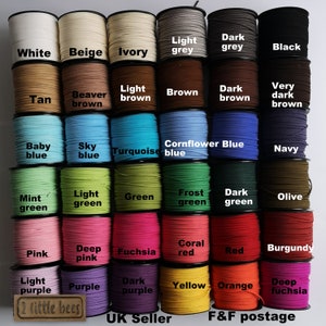 May include: A collection of 24 spools of cord in various colours, including white, beige, ivory, light grey, dark grey, black, tan, beaver brown, light brown, brown, dark brown, very dark brown, baby blue, sky blue, turquoise, cornflower blue, navy, mint green, light green, green, frost green, dark green, olive, pink, deep pink, fuchsia, coral red, red, burgundy, light purple, purple, dark purple, yellow, orange, and deep fuchsia. The spools are arranged in a grid pattern.
