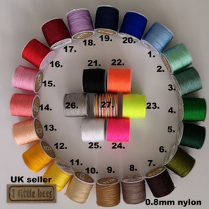 May include: A selection of 27 spools of 0.8mm nylon cord in various colours, arranged in a circle. The spools are numbered 1 to 27. The text "UK seller 2 little bees" and "0.8mm nylon" are also visible.
