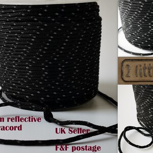 May include: A spool of 2mm black reflective paracord with white diamond-shaped reflective accents. The paracord is wound around a clear plastic spool. The text "2mm reflective paracord" and "UK Seller" is visible in the image.