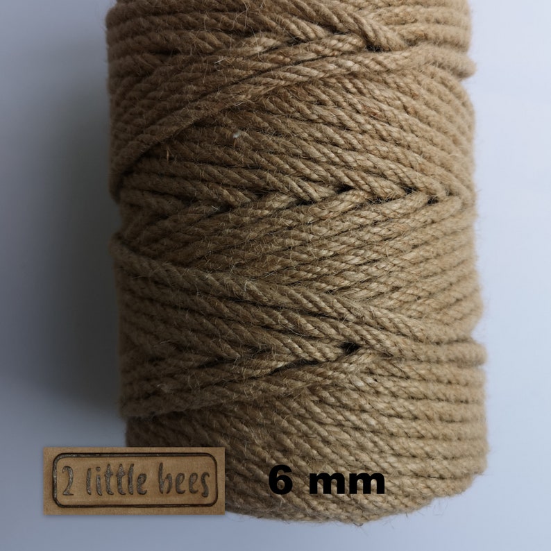 May include: A close-up of a spool of natural brown twine, 6 mm thick, with a label that reads "2 little bees".