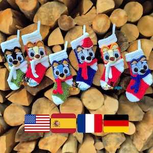 Könnte beinhalten: Gehäkelte Weihnachtsstrümpfe mit Cartoon-Hundegesichtern in verschiedenen Farben, darunter Rot, Blau und Grün. Jeder Strumpf hat eine weiße Manschette und eine kleine Schlaufe zum Aufhängen. Der Hintergrund ist ein Stapel Brennholz.