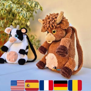 May include: Two plush cow-shaped bags. One is black and white with a pink nose, the other is brown with a fluffy mane and horns. Both have black straps. The bags are sitting on a light blue surface.