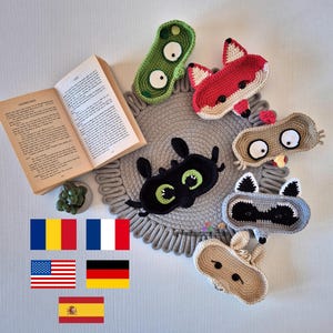 Könnte beinhalten: Ein Set aus sechs gehäkelten Tierkörben in verschiedenen Farben, darunter Grün, Rot, Braun, Schwarz und Grau. Die Körbe sind auf einer runden grauen Häkelmatte angeordnet. Die Körbe haben gestickte Augen und andere Gesichtsmerkmale.