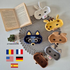 Puede incluir: Cinco bandejas de chucherías de crochet con forma de animal. Las bandejas tienen forma de conejo, jirafa, mapache, gato y oso. Las bandejas son de diferentes colores y tienen ojos y narices negros. Las bandejas están sobre una alfombra de crochet gris.