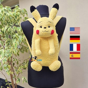 Puede incluir: Una mochila amarilla de ganchillo con forma de Pikachu, con orejas con puntas negras, mejillas rojas y una cara sonriente. La mochila tiene correas ajustables y se muestra en un maniquí negro. El diseño incluye brazos y pies.