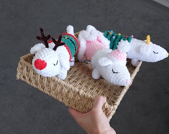 May include: Three white crocheted stuffed animals in a wicker basket. One animal is dressed as a reindeer, another is dressed as a Christmas tree, and the third is dressed in pink.
