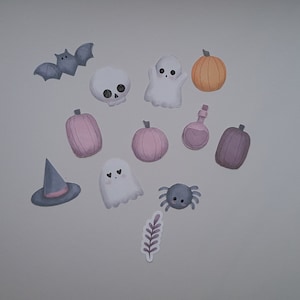 Op de afbeelding: Een set Halloween-stickers met een spook, een vleermuis, een heksenhoed, een spin, een schedel, een pompoen en een flesje met toverdrank. De stickers zijn allemaal in tinten roze, paars, oranje en grijs.