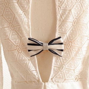 May include: White lace dress with a low back and a black and white bow tie detail.