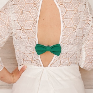 May include: White lace dress with a low back and a green bow tie accent.