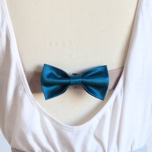 May include: A teal blue bow tie on a white tank top.