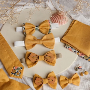 Peut inclure: Un ensemble de nœuds papillon jaune moutarde, une cravate assortie et un mouchoir de poche. Les nœuds papillon sont en tissu et en bois. La cravate et le mouchoir de poche sont en tissu. L'ensemble comprend également une paire de boutons de manchette.