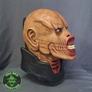 May include: A detailed, hand-painted, realistic horror mask of a creature with a large, open mouth, showing teeth. The mask is made of a flesh-toned material and has a black collar.