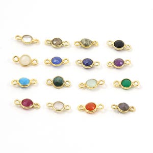 May include: Assortment of 16 gold-plated gemstone connector charms. Each charm features a different gemstone color, including turquoise, amethyst, ruby, and emerald.