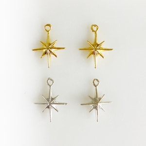 May include: Four star-shaped charms with a loop at the top. Two charms are gold and two charms are silver.