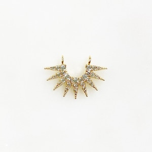 May include: Gold pendant with a starburst design, featuring clear sparkling stones.