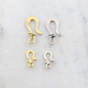 May include: Four gold and silver lobster clasps, two large and two small.
