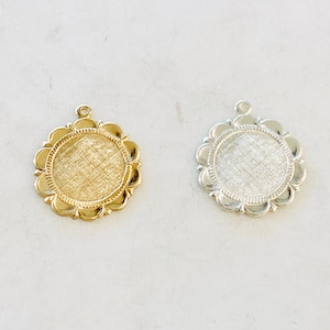 May include: Two round metal charms with a scalloped edge. The charm on the left is gold and the charm on the right is silver.