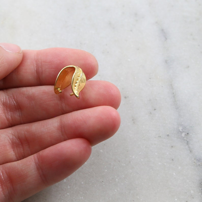 Puede incluir: Cierre de colgante en forma de hoja de oro para la elaboraci&oacute;n de joyas. El cierre est&aacute; hecho de metal y tiene un acabado liso y pulido.