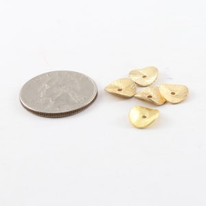 Puede incluir: Cinco cuentas de metal de forma triangular de color dorado con un agujero en el centro. Las cuentas son texturizadas y tienen un acabado ligeramente martillado. Las cuentas son aproximadamente del tama&ntilde;o de una moneda de 25 centavos de d&oacute;lar estadounidense.
