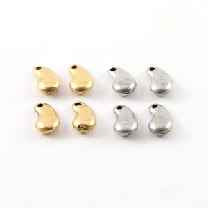 May include: Six metal charms in the shape of a teardrop. Two are gold and four are silver.