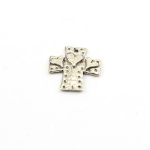 May include: Silver charm in the shape of a cross with three hearts on top.