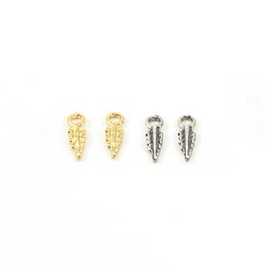 May include: Four small, decorative metal charms in the shape of a leaf. Two charms are gold and two are silver.
