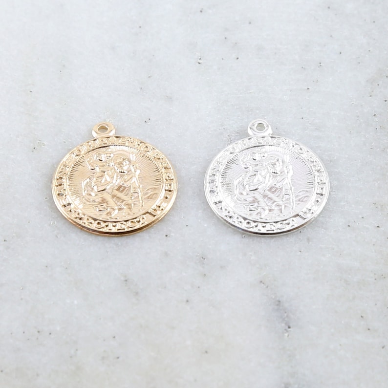 May include: Two round metal pendants with a raised image of a saint. One pendant is gold and the other is silver.