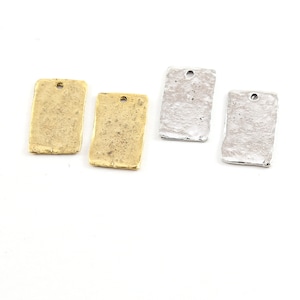May include: Four metal rectangular tags with a hole at the top. Two tags are gold and two tags are silver. The tags have a textured surface.