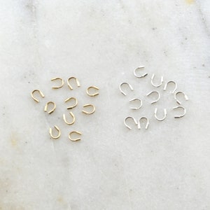 May include: Two groups of small, metal crimp end caps. One group is gold and the other is silver.