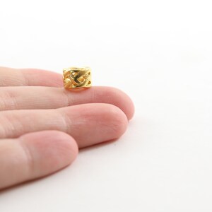 May include: A gold-colored metal bead with a woven design.