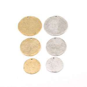 May include: Six round metal charms, three gold and three silver, with a textured surface. The charms have a hole at the top for attaching to jewelry or other crafts.