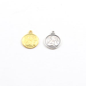 May include: Two angel charms, one gold and one silver, with a detailed design of a cherub with wings. The charms are round and have a loop at the top for attaching to jewelry.