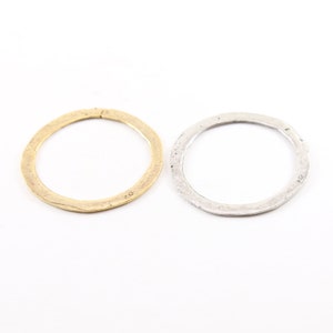 May include: Two simple metal rings, one gold and one silver, with a hammered texture. The rings are open and could be used for jewelry making or other crafts.