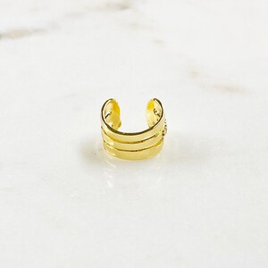May include: Gold ear cuff with three horizontal bands.