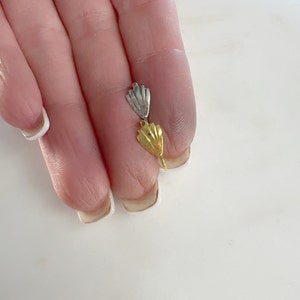 May include: Two metal clasps, one gold and one silver, with a fan-shaped design.
