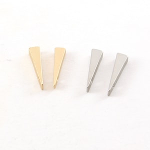 May include: Four minimalist earrings. Two are gold-toned, and two are silver-toned. Each earring is a solid, triangular shape with a small hole at the base. The earrings are displayed on a white surface.
