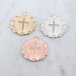 May include: Three round metal charms with a cross design. The charms are gold, silver, and rose gold.
