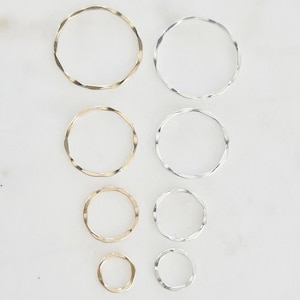 May include: A set of eight silver and gold jump rings in various sizes. The jump rings are all twisted and have a hammered finish.